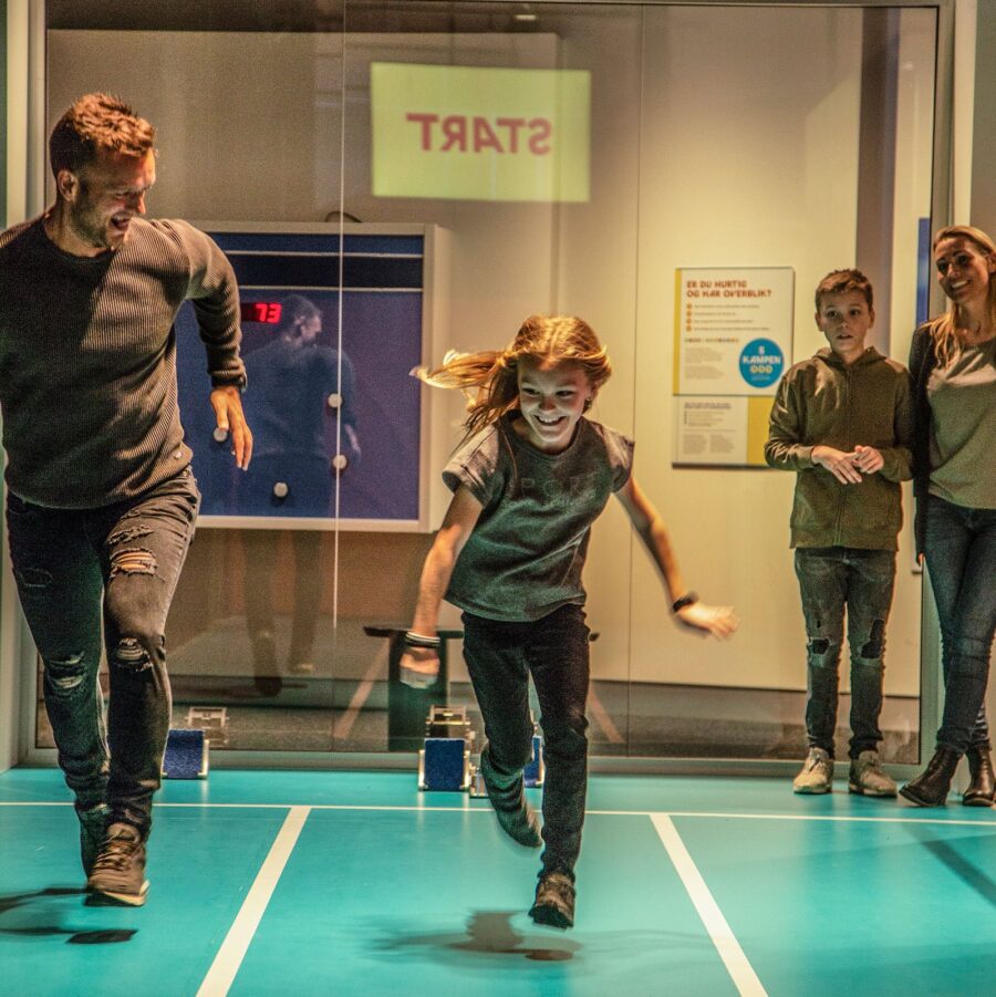 Barn prøver kræfter af løbebanen med forældre